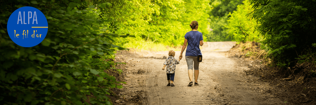 Une maman parcourt un chemin avec son enfant en lui tenant la main
